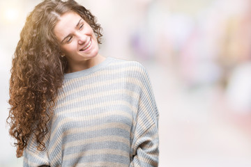 Beautiful brunette curly hair young girl wearing winter sweater over isolated background looking away to side with smile on face, natural expression. Laughing confident.