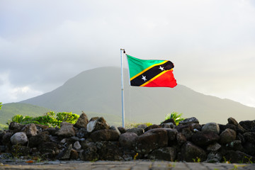 Flag of the Federation of St Kitts and Nevis floating in front of the Nevis volcano