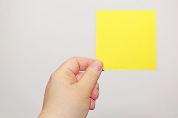 Hand hält gelben Notizzettel