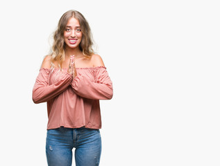 Beautiful young blonde woman over isolated background praying with hands together asking for forgiveness smiling confident.