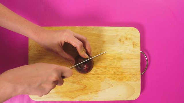 top view, female hand cuts fruit with a knife on a wooden board, maracuya. The concept of natural healthy food.