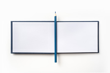 Top view of blue hardcover notebook and pencil
