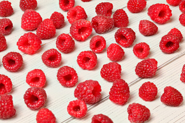 Raspberries freshly picked from garden spilled on white boards desk.