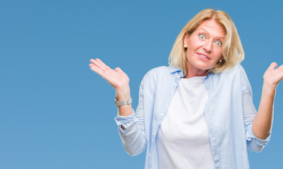 Fototapeta premium Middle age blonde woman over isolated background clueless and confused expression with arms and hands raised. Doubt concept.