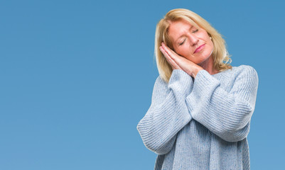 Middle age blonde woman wearing winter sweater over isolated background sleeping tired dreaming and posing with hands together while smiling with closed eyes.