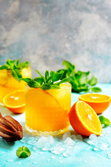 Cold summer orange lemonade with mint and ice cubes.