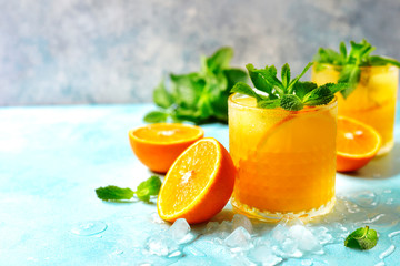 Cold summer orange lemonade with mint and ice cubes.