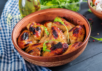 Baked chicken wings in bowl on wooden table.