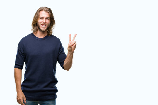 Young handsome man with long hair wearing winter sweater over isolated background smiling with happy face winking at the camera doing victory sign. Number two.