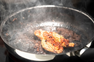 Schnitzel cooking in a pan.