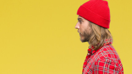 Young handsome man with long hair wearing red cap over isolated background looking to side, relax profile pose with natural face with confident smile.