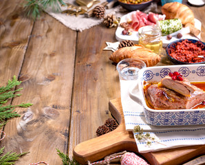 Baked duck and various snacks for the Christmas table. Rustic table with decor and different food for the holiday. Top view. Free space for text. Baking dish with a pattern.