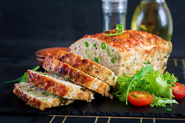 Tasty homemade ground  baked chicken meatloaf with green peas and broccoli on black table. Food american meat loaf.