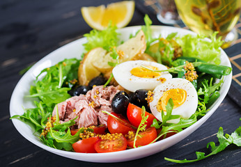 Healthy hearty salad of tuna, green beans, tomatoes, eggs, potatoes, black olives close-up in a bowl on the table. Salad Nicoise. French cuisine.