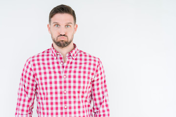 Fototapeta premium Young handsome man wearing shirt over isolated background puffing cheeks with funny face. Mouth inflated with air, crazy expression.