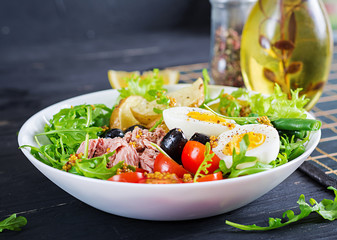 Healthy hearty salad of tuna, green beans, tomatoes, eggs, potatoes, black olives close-up in a bowl on the table. Salad Nicoise. French cuisine.