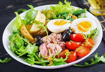 Healthy hearty salad of tuna, green beans, tomatoes, eggs, potatoes, black olives close-up in a bowl on the table. Salad Nicoise. French cuisine.
