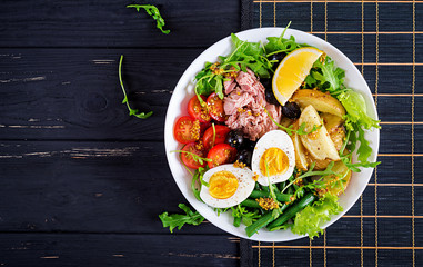 Healthy hearty salad of tuna, green beans, tomatoes, eggs, potatoes, black olives close-up in a bowl on the table. Salad Nicoise. French cuisine. Top view. Flat lay