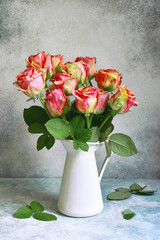 Bouquet of pink roses in a white vintage pitcher or jug.