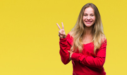 Young beautiful blonde woman wearing red sweater over isolated background smiling with happy face winking at the camera doing victory sign. Number two.