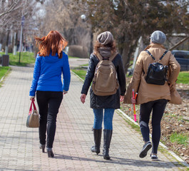 Three girls are walking along the pavement