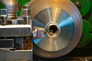 Machining of a round part on a lathe, facing by a worker on a mechanical feed. Chips fly in different directions.