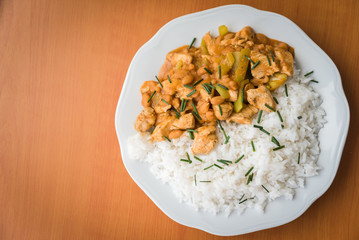Chicken curry nuggets with rice and bean on a white plate. Space on left side