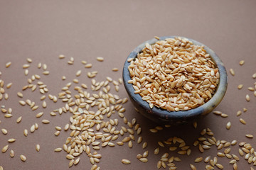 White flax seeds in a bowl on a brown background