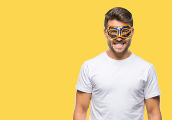 Young handsome man wearing carnival mask over isolated background with a happy and cool smile on...