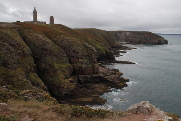 Fototapeta na wymiar Cold northern cliffs and the Celtic Sea with a lighthouse in French Brittany Pointe du Decolle France