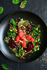 Delicious sald with chard leaves, beetroot and grapefruit slices on a black plate.Top view.