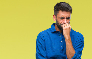 Adult hispanic man over isolated background looking stressed and nervous with hands on mouth biting...