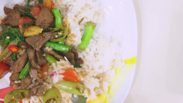 someone eats with a fork, rice with liver, top view food on a white dish.