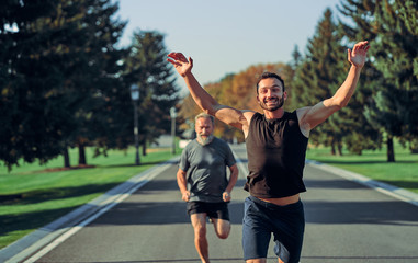 The young and old sportsmen running on the road