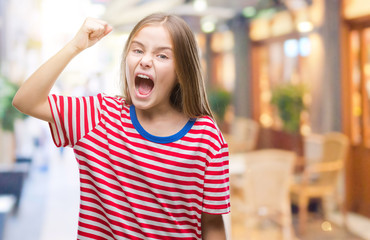 Young beautiful girl over isolated background angry and mad raising fist frustrated and furious...