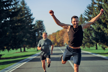 The young and old sportsmen running on the road