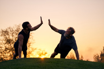 The two sportsmen push up together on the sunset background