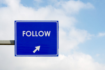 Follow word displayed on blue road sign