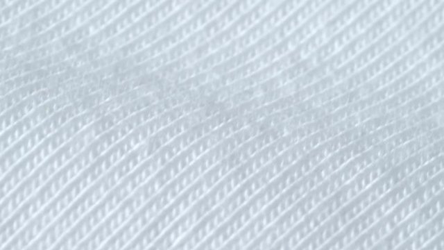 Textile background - white cotton lycra fabric with jersey (stockinette) structure. Weave pattern of threads close up.