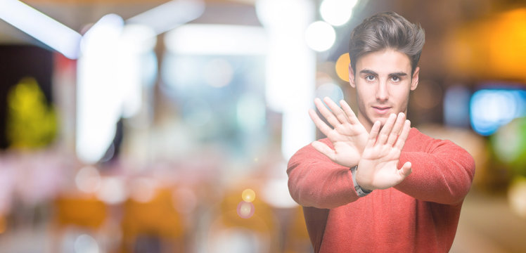 Young handsome man over isolated background Rejection expression crossing arms and palms doing negative sign, angry face