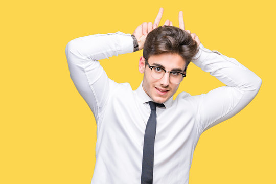 Young business man wearing glasses over isolated background Posing funny and crazy with fingers on head as bunny ears, smiling cheerful