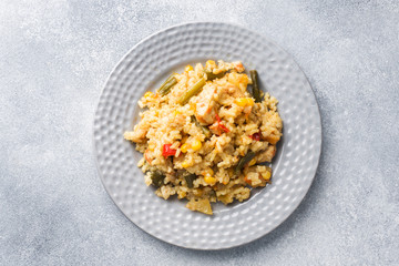 Pilaf with vegetables and chicken in a gray plate on a gray background.