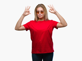 Obraz na płótnie Canvas Young caucasian woman wearing sunglasses over isolated background relax and smiling with eyes closed doing meditation gesture with fingers. Yoga concept.