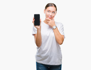 Young beautiful caucasian woman showing smartphone screen over isolated background serious face...