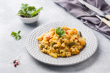 Pilaf with vegetables and chicken in a gray plate on a gray background.