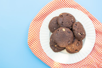 Chocolate cookies on white plate and orange fabric top view