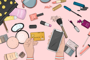 Online store concept with women's cosmetics. Women's hands with a credit card and smartphone pay for purchases online. Payment by credit cards online. The view from the top.