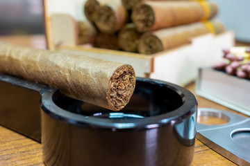 Brown cigar on a black ashtray. Vintage. Luxury. Smoking. Bad habit. Beautiful background