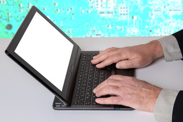 Hands of a unrecognizeable businessman working with  a modern portable computer on a white table. Computer in front of abstract bright technology background.