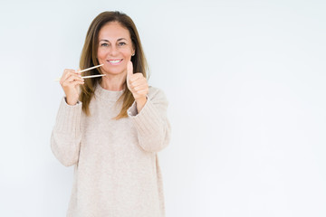 Middle age woman holding asian chopsticks over isolated background happy with big smile doing ok sign, thumb up with fingers, excellent sign